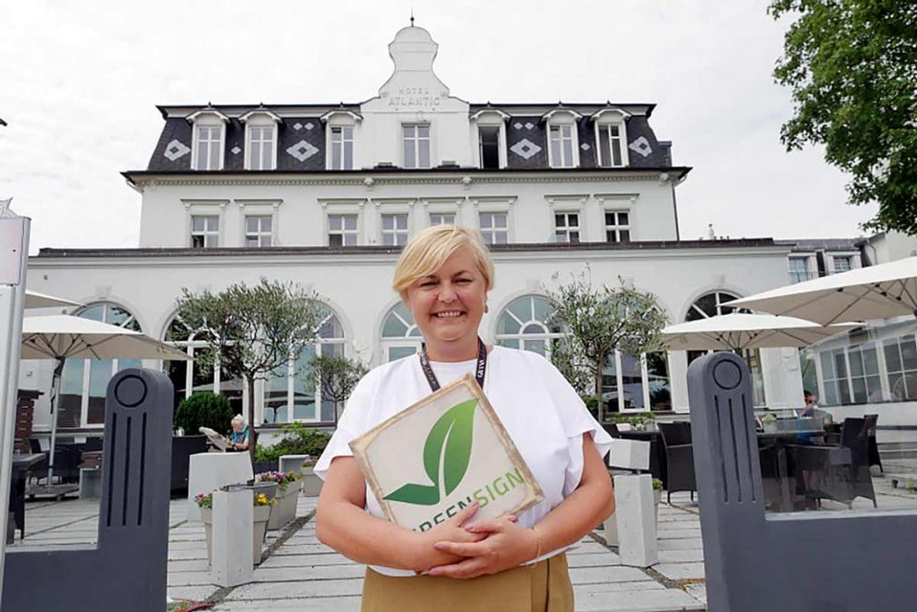 Petra Sowada vor dem SEETELHOTEL Strandhotel Atlantic, welches dieses Jahr GreenSign-zertifiziert wurde.